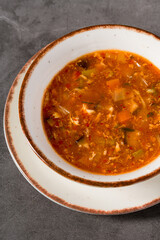 Hot and sour Asian soup with vegetables in white bowl