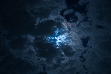 Full moon shining through dramatic dark clouds at night