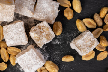 Turkish delight on the table, Turkish delight cubes and peanuts on a black slate surface, close up,...