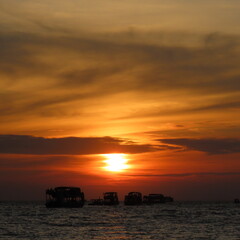bright red sunset with shadows of boats in the water