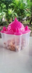 A plastic jar with a pink lid that resembles the shape of a mosque dome.