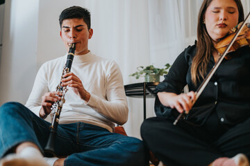 Musicians playing a clarinet and a violin together in a relaxed indoor setting, seated on the...