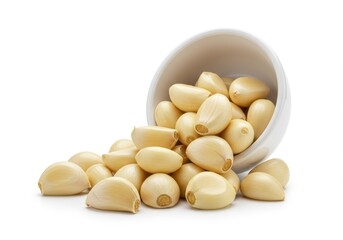 Peeled garlic cloves spilling out of a bowl isolated on white background