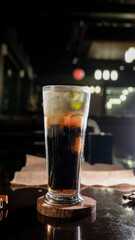 A tall glass filled with iced black coffee mixed with jelly cubes and topped with fresh mint...