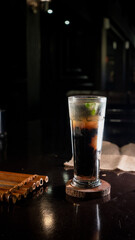 A tall glass filled with iced black coffee mixed with jelly cubes and topped with fresh mint...