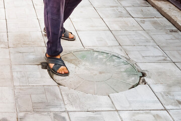 Worker standing near a drainage pit while inspecting septic system access point
