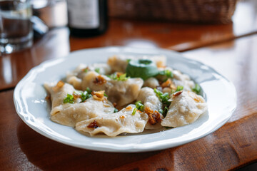 Plate of traditional pierogi garnished with fried onions and herbs served on a wooden table. Polish pierogi, heritage recipes, culinary authenticity, traditional dumplings