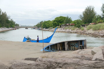 Two Traditional Blue Boats Resting on Sandy Beach Near Calm Water
