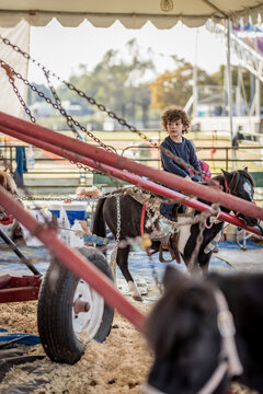 Young boy rides pony carousel under event tent