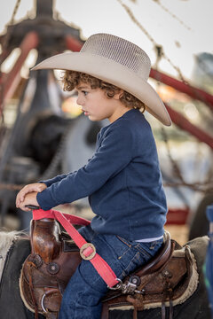Boy in cowboy hat rides pony at a fair under a large tent