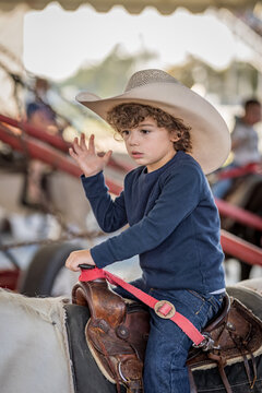 Young boy in cowboy hat rides pony at outdoor fair