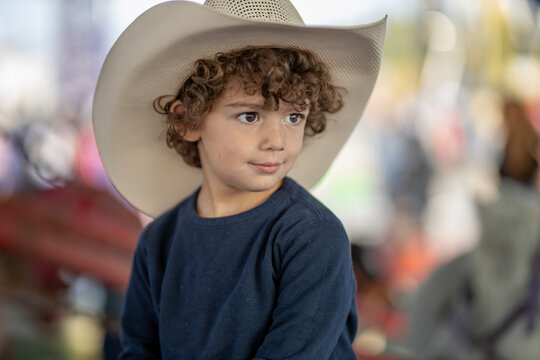 Young boy in cowboy hat gazes to the side with a slight smile