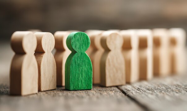 Single green wooden figure amidst a line of beige figures