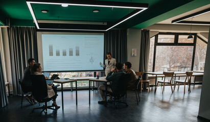 Group of colleagues engaged in a business presentation within a stylish conference room setting.