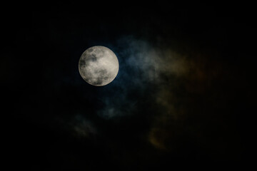 full moon in the midnight behind the cloudy sky