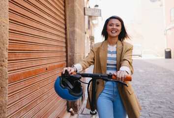 Asian student using e scooter in a town