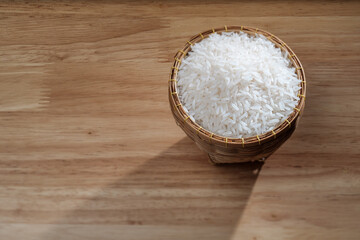 raw Thai's jasmine rice in Thai's traditional style bamboo's bowl on wooden dinner table
