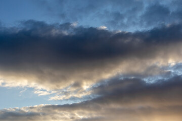 Dark clouds with patches of blue sky at sunset