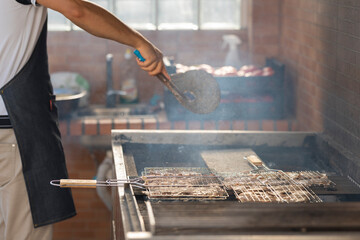 Chef grilling meat on barbecue with smoke in restaurant kitchen