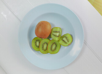 Kiwi fruit on a blue plastic plate, top view, some slices arranged in bright colors. Fruit, food concept, high in vitamins.