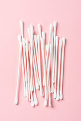 White cotton swabs on pink background.