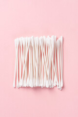 White cotton swabs on pink background.