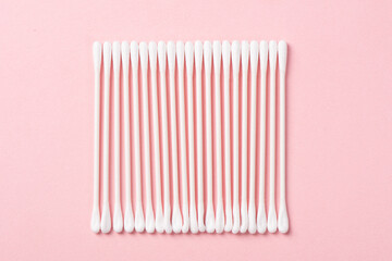 White cotton swabs on pink background.