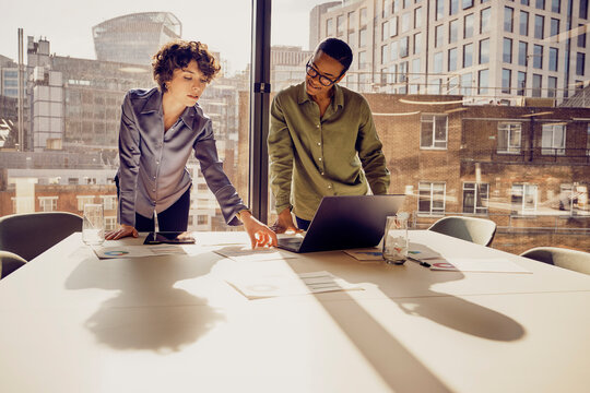 Businesswomen discussing over laptop standing at desk in office