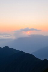 Fototapeta premium Sunset Over Mountain Range with Clouds and Layered Blue Hues