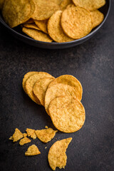 Crispy potato chips on black table.