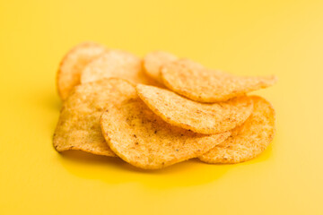 Crispy potato chips on yellow background.