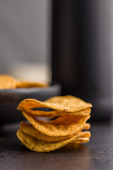 Crispy potato chips on black table.