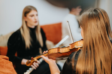 A violinist is performing while another individual listens intently, creating a warm atmosphere.