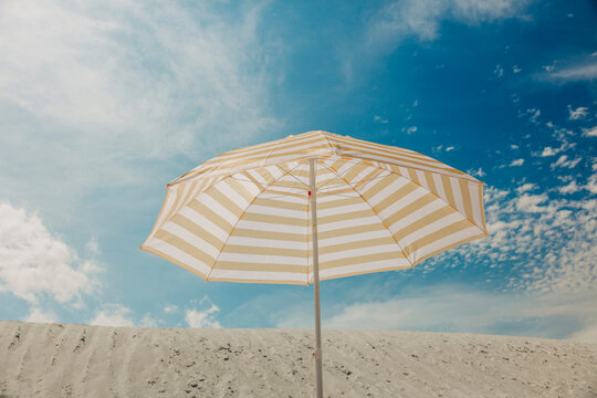 Yellow striped umbrella on sandy beach under blue sky in summer