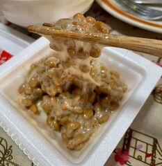A photo of stirring natto, Japanese fermented soy bean, with bamboo chopsticks to create stretchy...