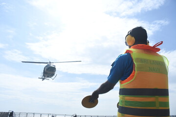 Camouflage colour bell 212 helicopter in hover over a naval military ship and ready for departure	