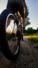 Young man riding bike on gravel road at sunset. Cyclists Going Uphill at Sunset