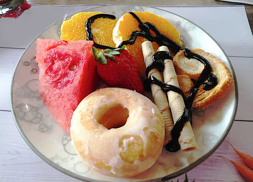 Plato con postre dulce de donut, fruta, barquillo, palmera y sirope de chocolate lleno de az&uacute;car y glucosa no apto para diab&eacute;ticos e hipergluc&eacute;micos