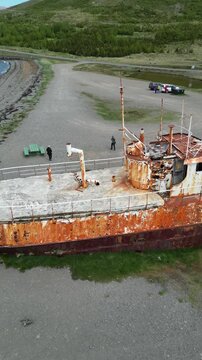 Aerial view of the rusted, decaying Gardar BA 64 shipwreck contrasting against the dark sand and blue waters, &Iacute;safjor&eth;ur, Iceland.