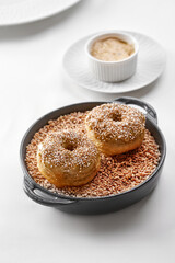 Two creative savory doughnuts with meat rillette and crunchy topping, served on a bed of grain in a...