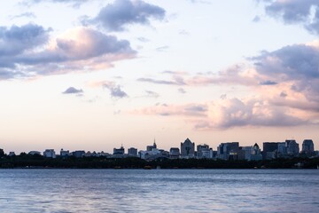 City skyline at dusk with river and clouds.