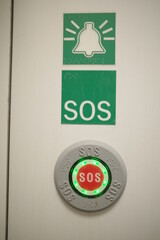 Green sign with a bell on it and the word SOS written in white