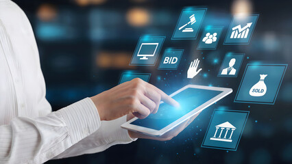 Modern professional uses tablet to engage with digital auction interface showcasing bid, sale, and financial growth icons in a dynamic business concept