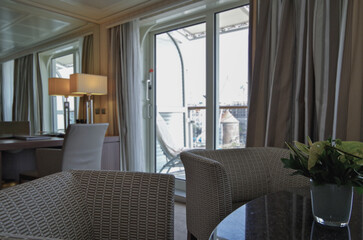 Luxurious suite stateroom cabin room onboard luxury yacht cruise ship cruiseship liner with bedroom and living area in purple and creme with wood in modern Art Deco interior design