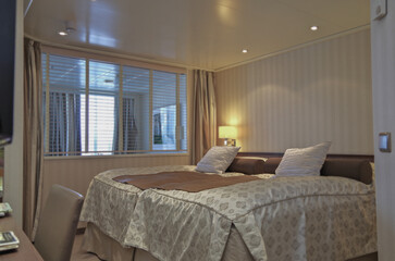 Luxurious suite stateroom cabin room onboard luxury yacht cruise ship cruiseship liner with bedroom and living area in purple and creme with wood in modern Art Deco interior design