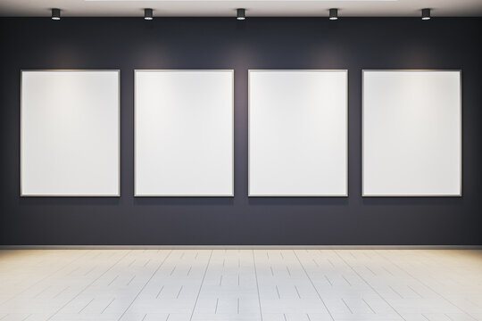 Modern art gallery interior with four blank vertical frames on dark wall under spotlights in clean exhibition room. 3D Rendering. 3D Rendering