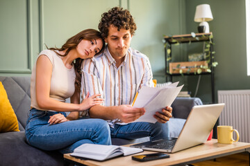 Couple discussing mortgage loan while checking home finances. They are checking financial documents...