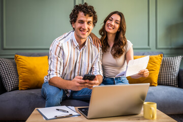 Couple discussing home finance while checking bills. They are checking financial documents and...
