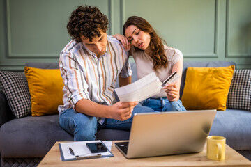 Couple discussing home finance while checking bills. They are checking financial documents and...