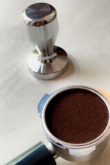 Barista prepares coffee powder in bottomless container and tampers the coffee powder.